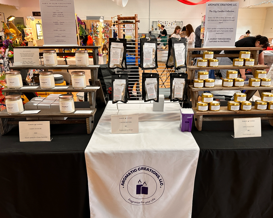 Display of candles at a trade show with 'Aromatic Creations, LLC' branding.